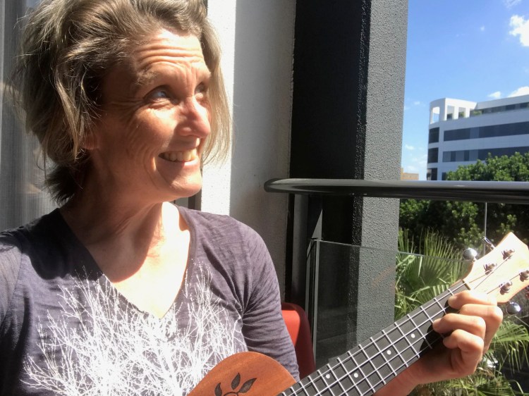 woman playing ukulele on balcony